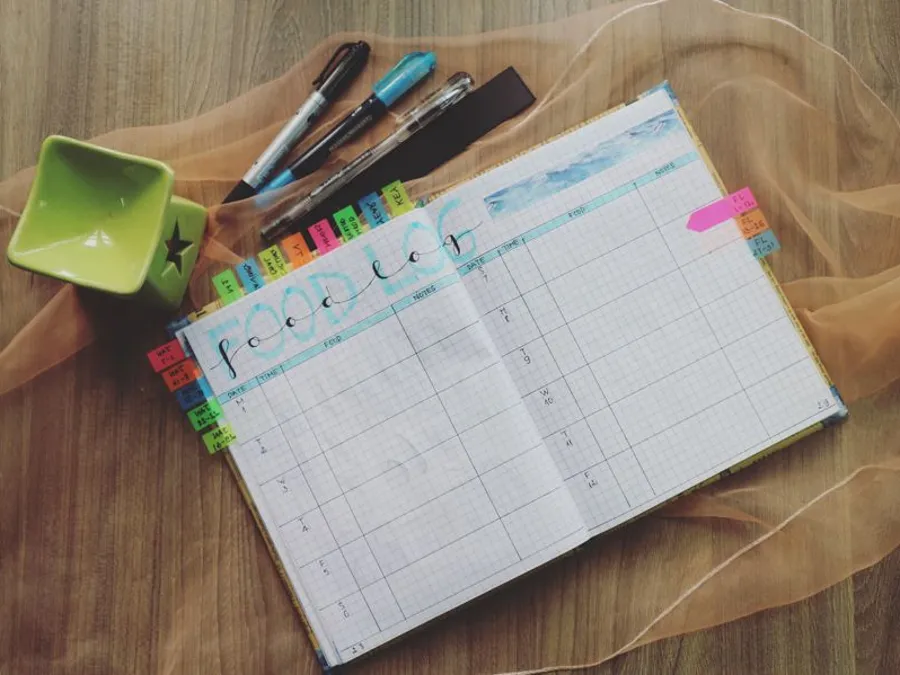 Opengeslagen planner met pennen op een houten bureau