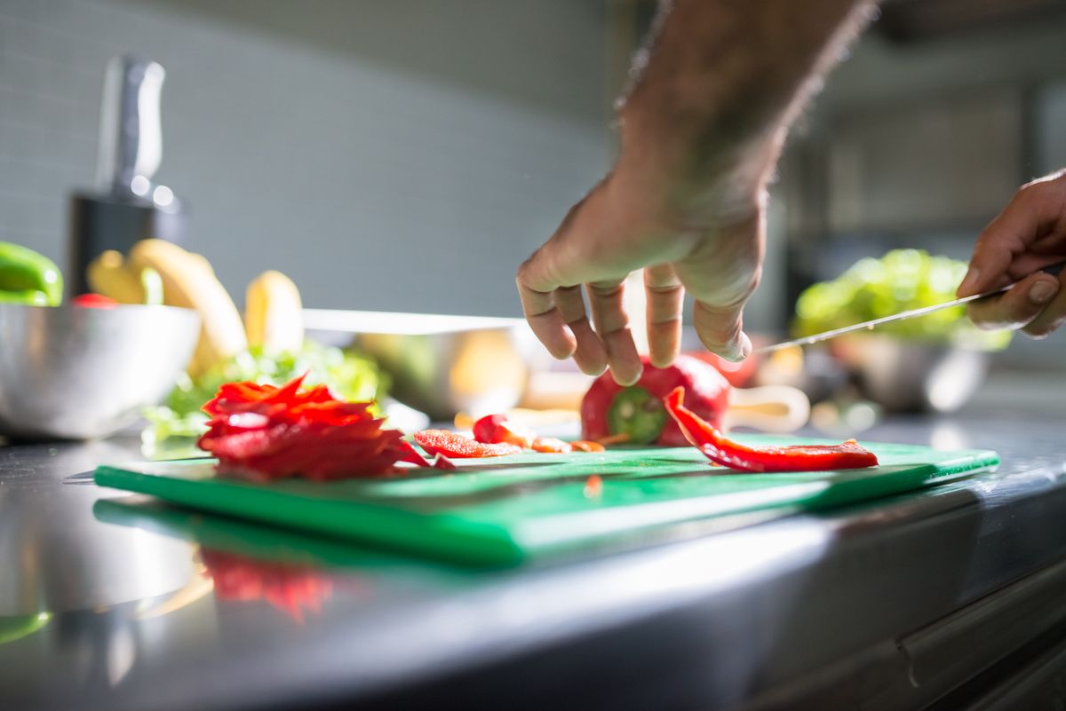 Iemand snijdt paprika op een snijplank