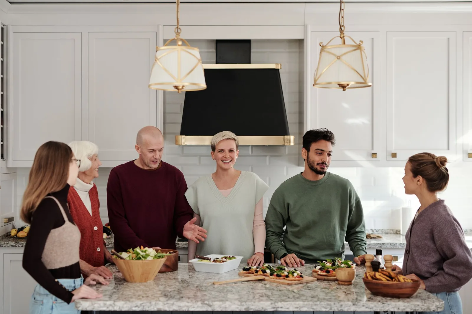 A multi-generational family enjoying a meal preparation together in a bright kitchen.