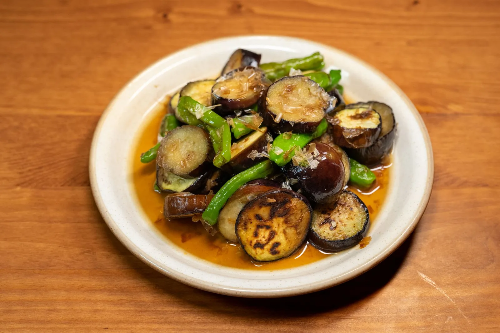 A vibrant dish of stir-fried eggplant and green peppers served on a white plate.