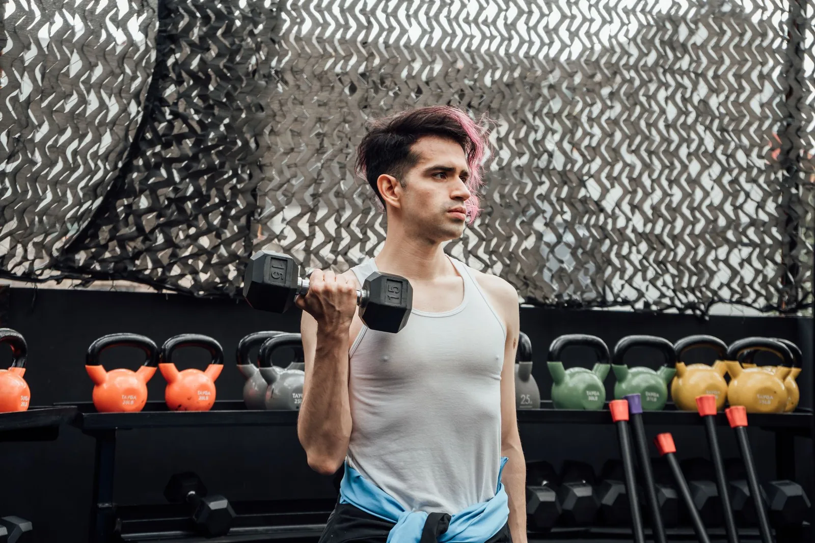 A young man lifting a dumbbell in an outdoor gym in Mexico City, promoting fitness and a healthy lifestyle.