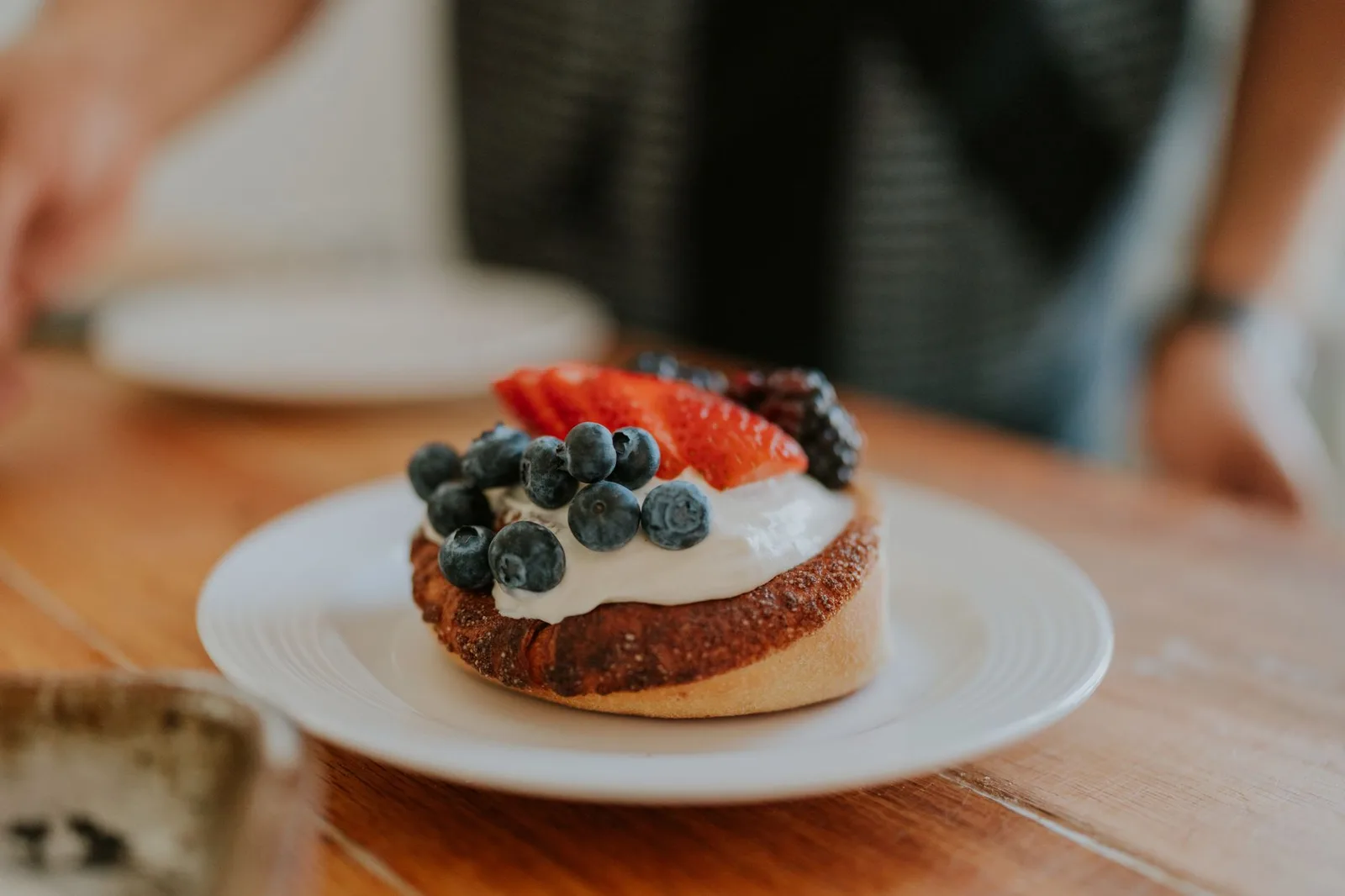Close-up of a fruit tart topped with blueberries, strawberries, and cream, perfect for dessert lovers.