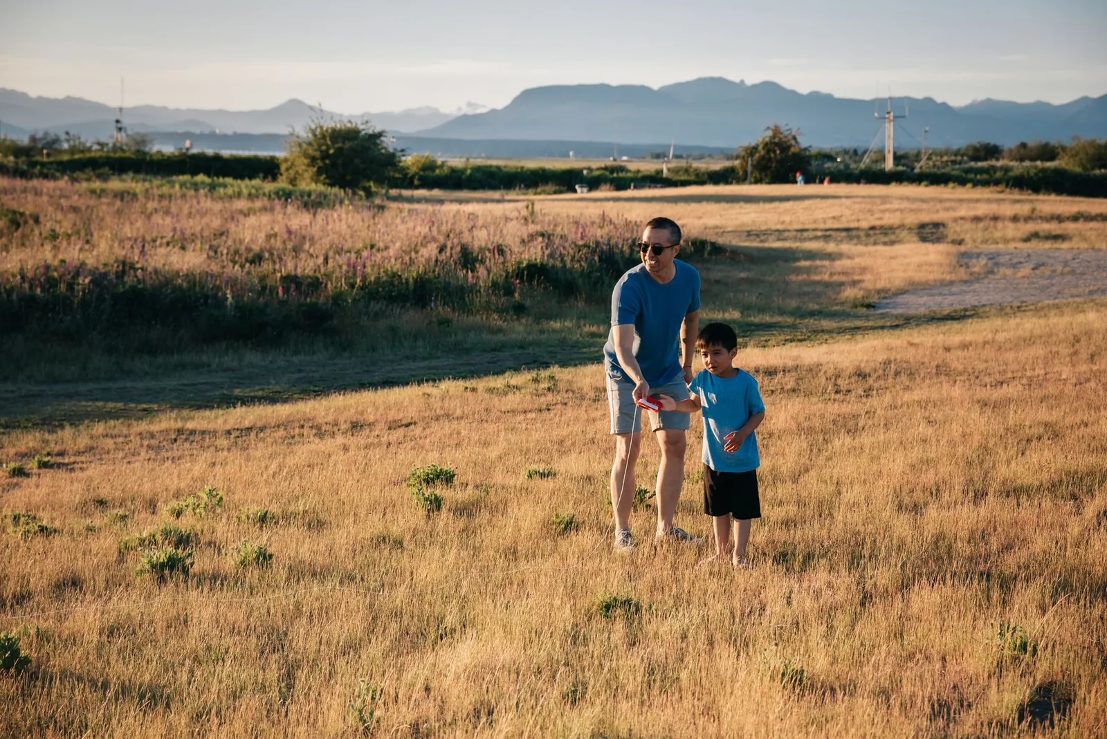 Father and son playing together in a scenic field, capturing a moment of leisure and bonding.