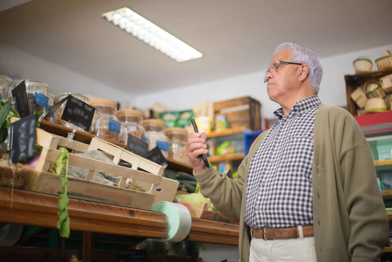 Senior man shopping in a Portuguese store, examining products with focus.