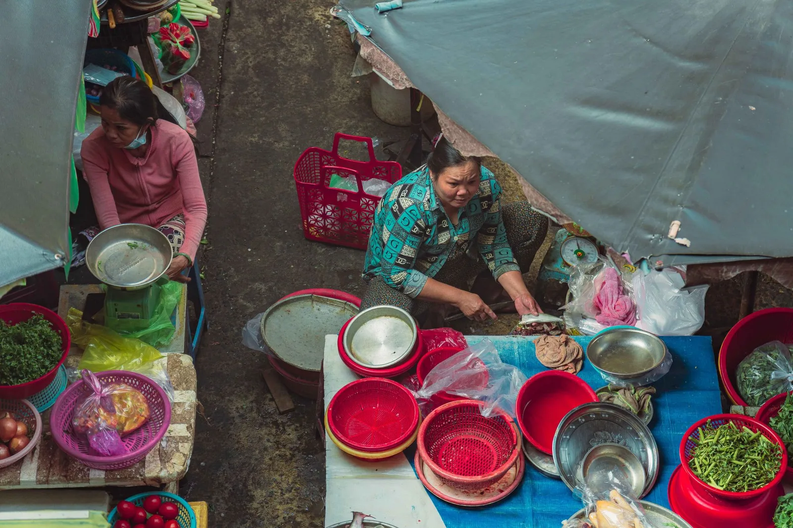 Two women selling produce at an outdoor market in Ho Chi Minh City, Vietnam.