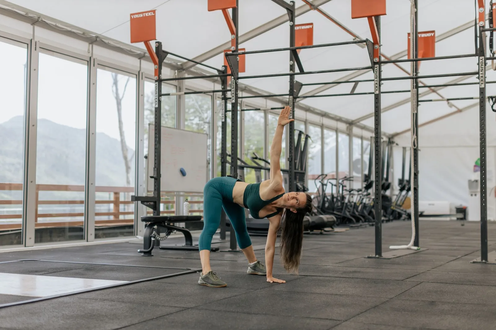 Buikvet verliezen: een haalbare aanpak met voeding en beweging — Caucasian woman stretching in a modern gym environment, promoting fitness and exercise.