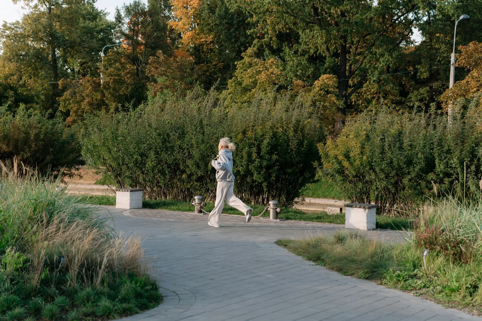 Intermittent fasting: praktisch afvallen met een klein budget — Elderly woman staying active by jogging in a scenic park surrounded by lush greenery.
