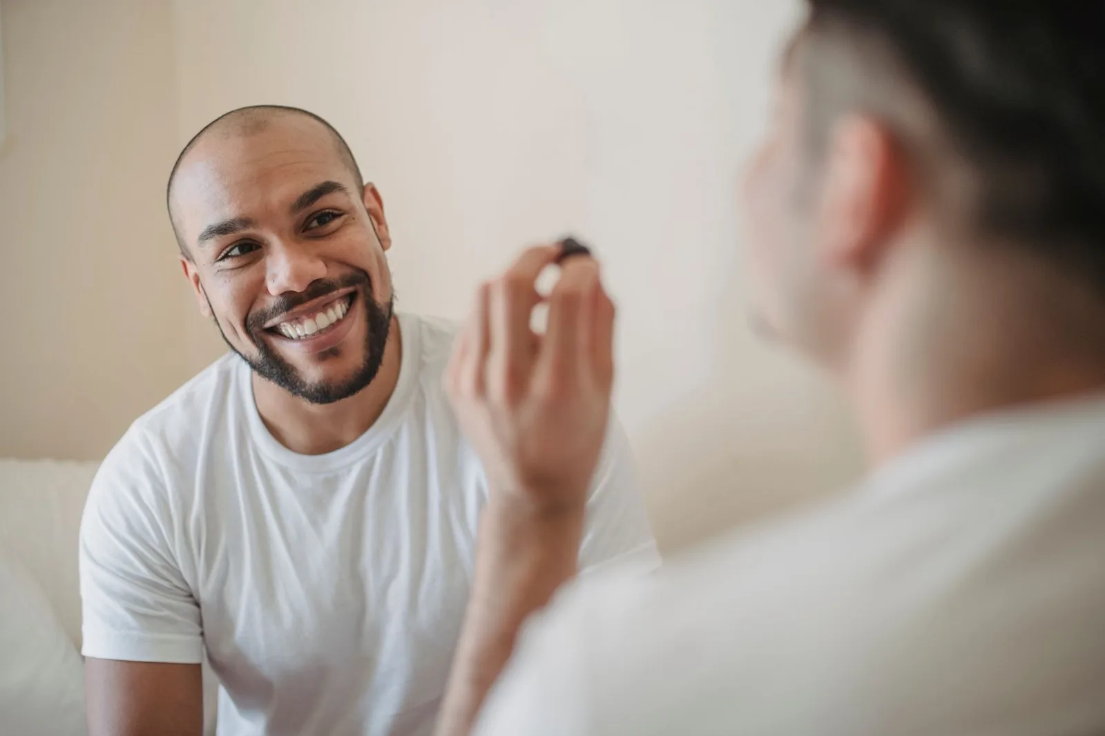 Two men smiling and engaging in a light-hearted moment indoors.