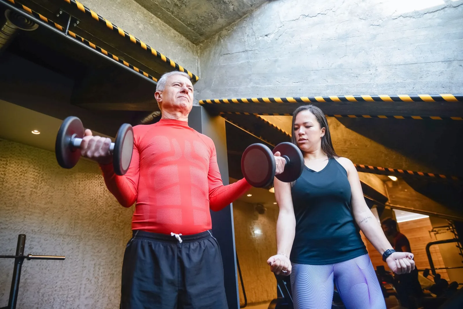Senior man and woman working out with dumbbells indoors, promoting a healthy and active lifestyle.