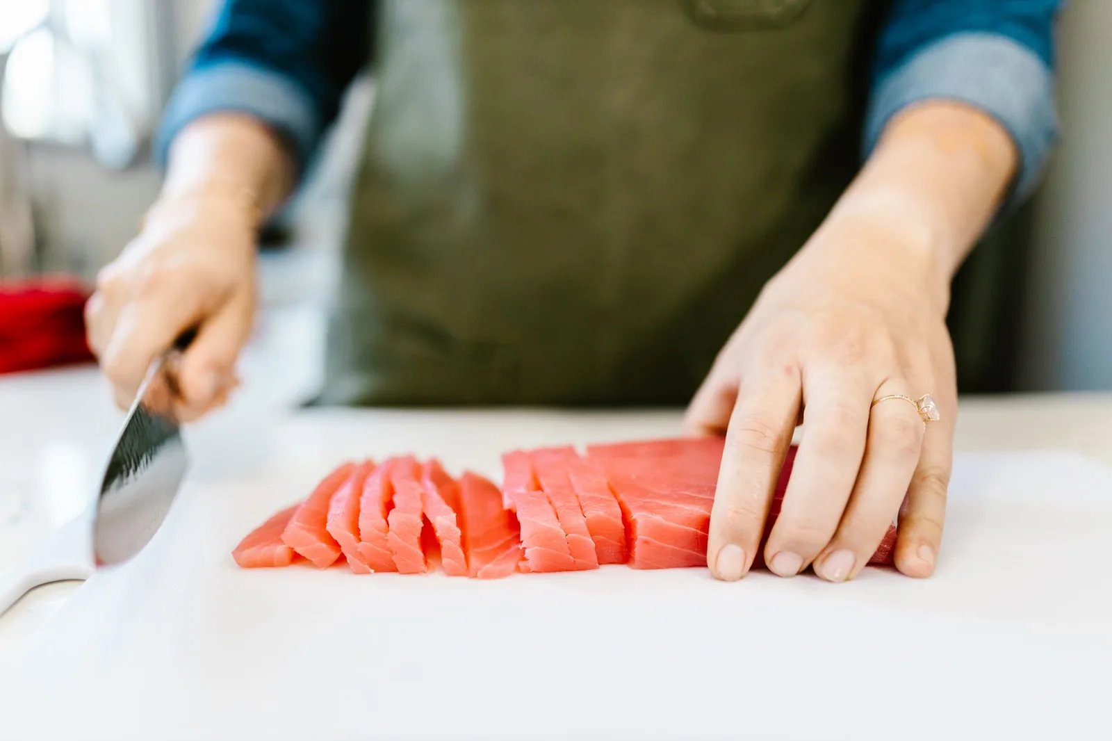 Water drinken en afvallen: hoeveel heb je per dag nodig? — Close-up of hands slicing fresh salmon fillet on a cutting board, ideal for seafood and cooking content.